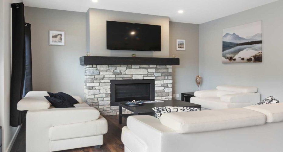 Natural gas fireplace in the living room brings together the warm, rich palette of the LVP flooring and the timeless color of the walls