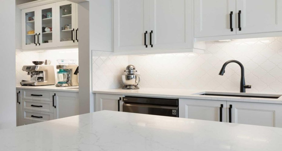 View from gleaming quartz-topped island to custom butler’s pantry