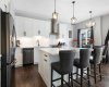 View of kitchen with breakfast bar seating at the oversized island complete with pull-out recycling and trash storage