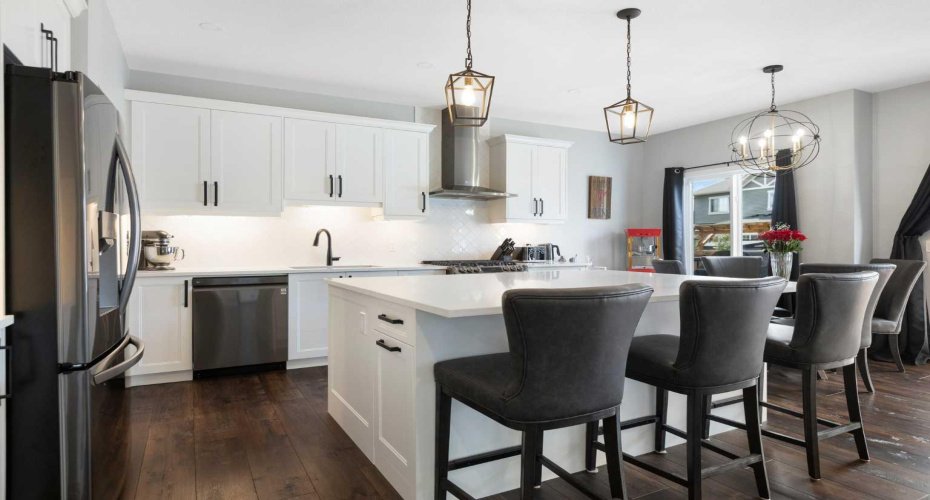 View of kitchen with breakfast bar seating at the oversized island complete with pull-out recycling and trash storage