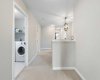 Hallway view of laundry room which has shelves for laundry & linen