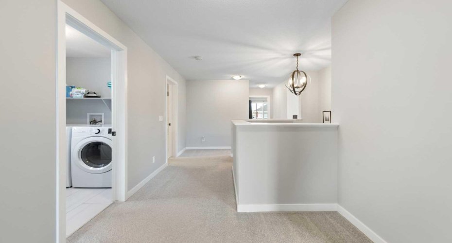 Hallway view of laundry room which has shelves for laundry & linen