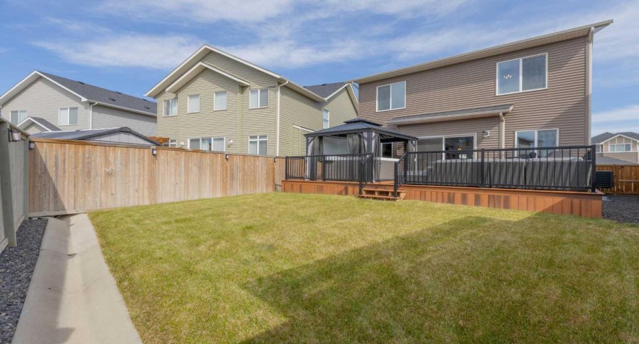 Fenced back yard with view of composite deck that runs the length of the house;  gazebo and hot tub included