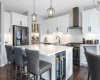 Oversized quartz-topped island includes beverage fridge & breakfast bar seating. View to butler's pantry