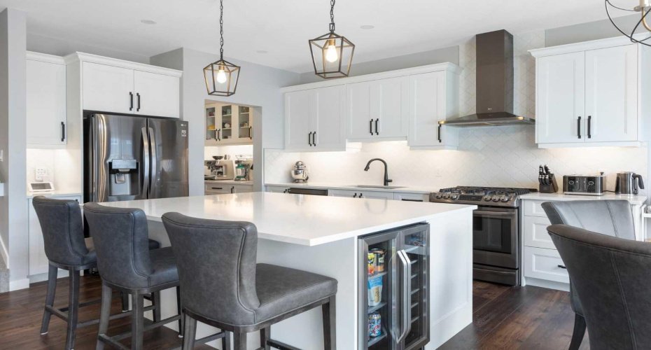 Oversized quartz-topped island includes beverage fridge & breakfast bar seating. View to butler's pantry
