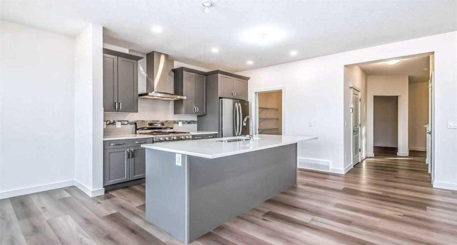 Kitchen equipped with quartz countertops, a large central island, stainless steel appliances, a gas range, and an upgraded chimney-style hood fan