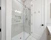 Beautifully tiled shower with glass door, 12” x 24” tile flooring and shower walls, tiled niche, timer exhaust fan, and wood-front medicine cabinet.