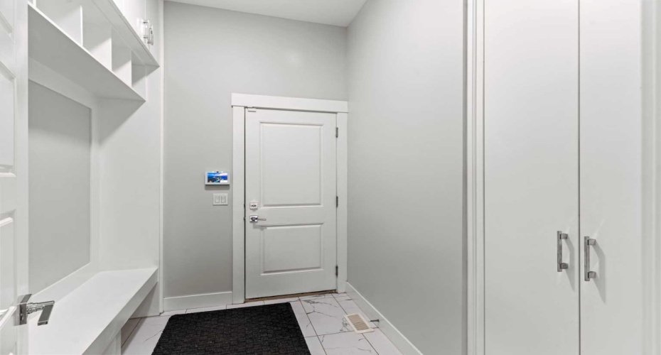 A thoughtfully designed private mudroom with direct access to the TRIPLE ATTACHED GARAGE features durable ceramic tile flooring and floor to ceiling built in storage, delivering exceptional organization and everyday convenience.