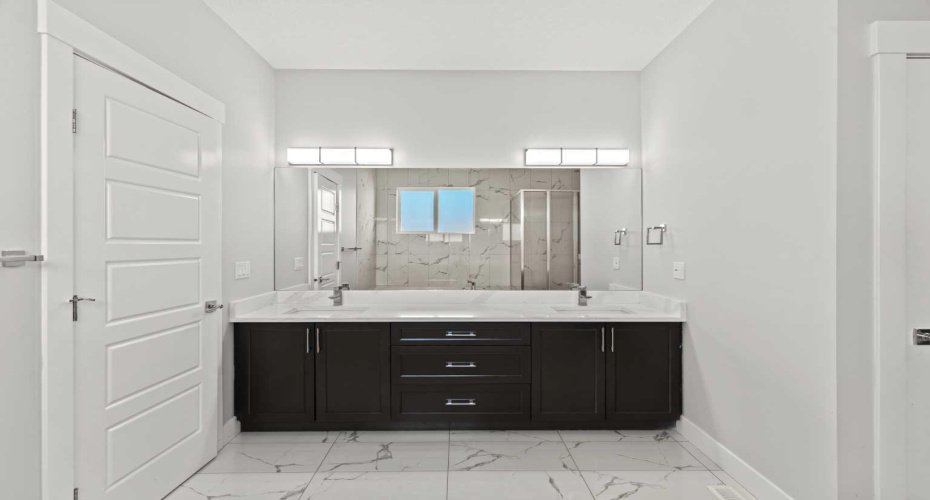 A refined double vanity with sleek quartz countertops anchors this 5 piece ensuite, offering generous space and polished finishes that elevate the daily routine into a luxury experience.