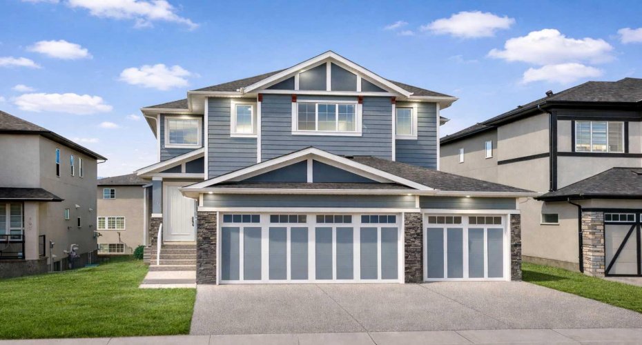 A commanding Kinniburgh home showcasing a LUXURY STONE AND WOOD EXTERIOR, expansive 6-CAR PARKING, and an OVERSIZED TRIPLE ATTACHED GARAGE — delivering striking architectural presence and exceptional functionality just moments from Chestermere Lake.