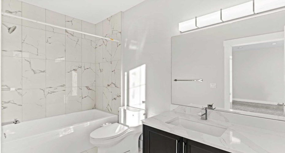 The secondary primary suite is complemented by a stylish 3 piece ensuite featuring a full tub with tiled surround and spacious vanity, combining comfort and functionality in a beautifully finished space.