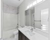 The third bedroom is complemented by a connected full bathroom featuring modern tile work, a sleek quartz vanity, and a tub shower combination for everyday comfort and convenience.