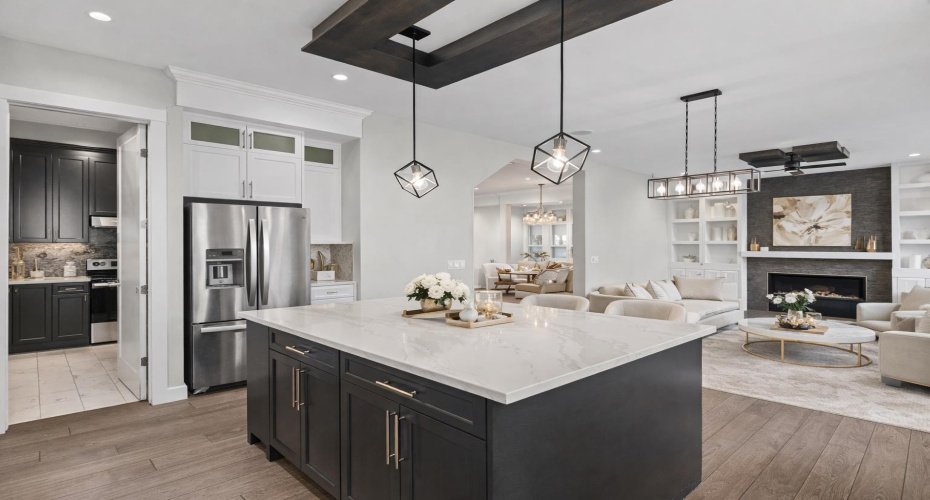 From the heart of the kitchen, the oversized quartz island overlooks the inviting second living area while offering a glimpse into the fully appointed SPICE KITCHEN, all enhanced by striking designer lighting that elevates the home’s modern luxury aesthetic.