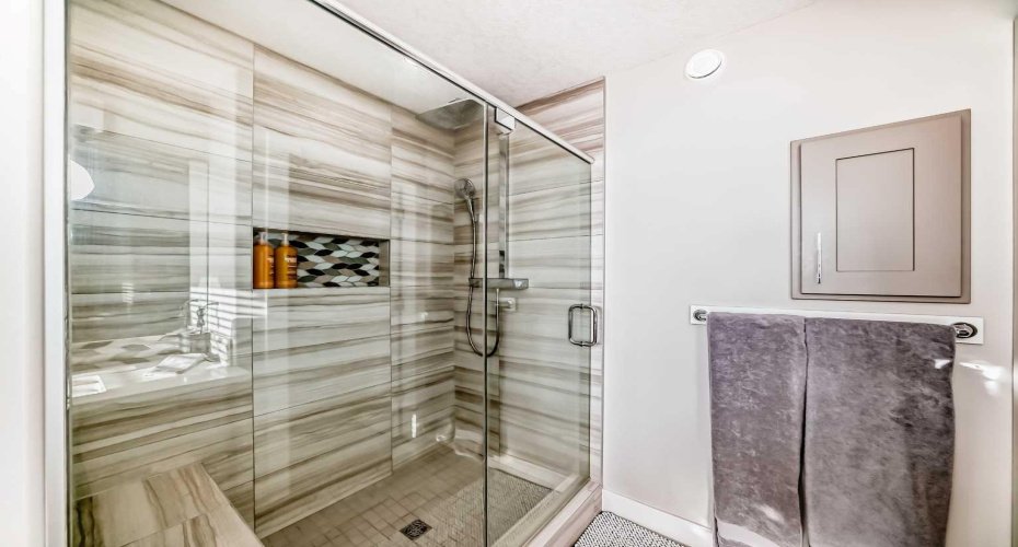 Glass-enclosed ensuite with built-in bench and niche.