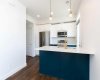 Stylish kitchen featuring 36” upper cabinetry with crown molding,  quartz countertops, two-tone cabinetry, soft-close drawers, a breakfast bar, and Samsung stainless steel appliances