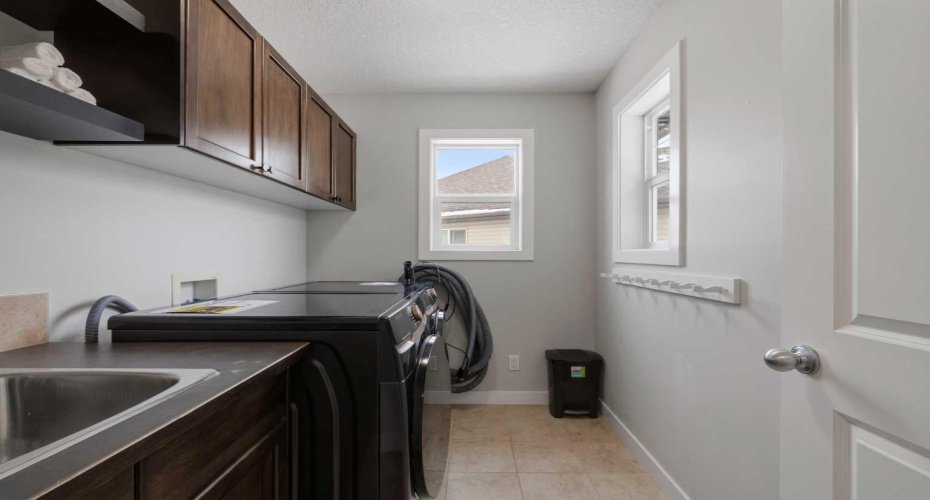 Upstairs laundry with sink and cabinetry.