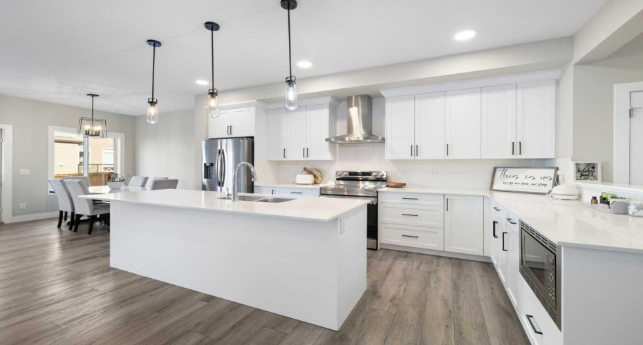 Upscale, chef's style kitchen with island, quartz counters & stainless-steel appliances including a built-in microwave.