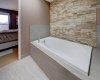 Deep Soaker tub with stone feature wall and a skylight