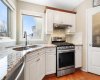 The kitchen features a gas stove and large windows that bring in abundant natural light...