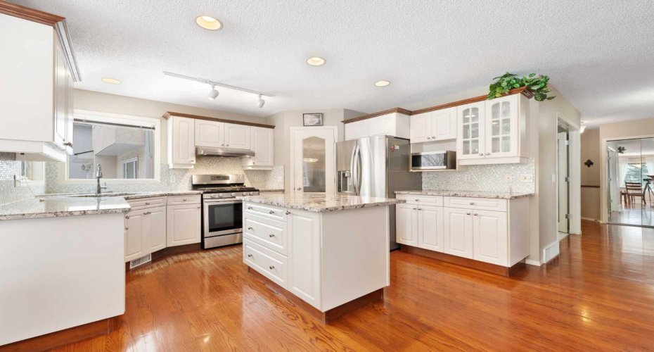The kitchen features granite countertops, a corner pantry, a central island, and ample cabinetry....