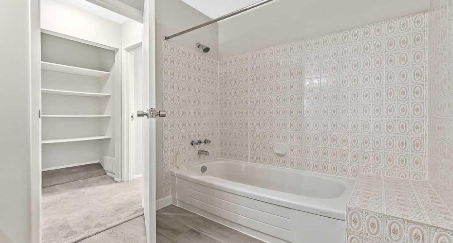Classic full bathroom layout with a tub and convenient built-in linen storage just outside the door.