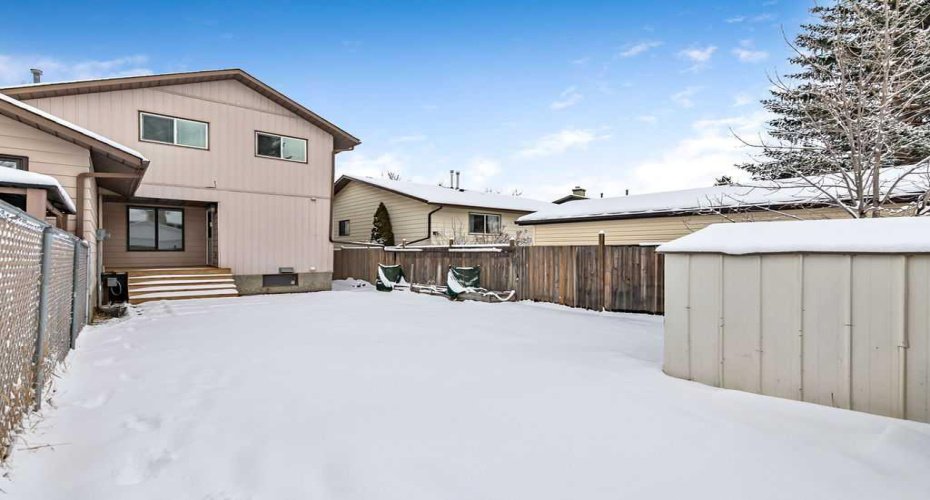 View of the home from the backyard showcasing the new deck and the generous outdoor space surrounding it.