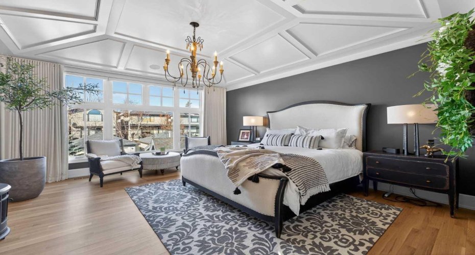 Bright and serene primary suite with elaborate ceiling detail and motorized blackout drapes and blinds.