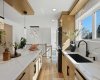 Sun-filled kitchen with quartz countertops, large island, modern cabinetry, black fixtures, and stylish pendant lighting.