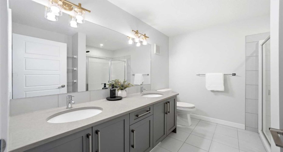 A well-designed primary ensuite with dual vanities and granite countertops.