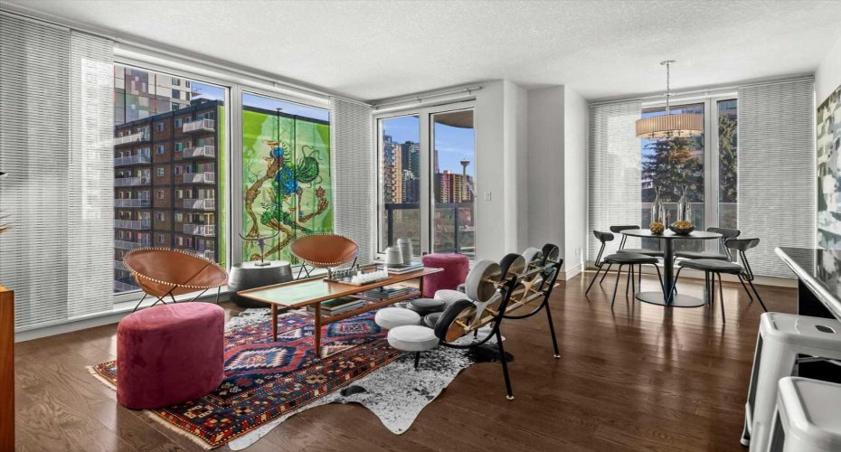 The corner living room catches light from two directions all day long. The Calgary Tower is visible through one set of windows while a large-scale street mural fills another, giving the room a view that genuinely stops people.