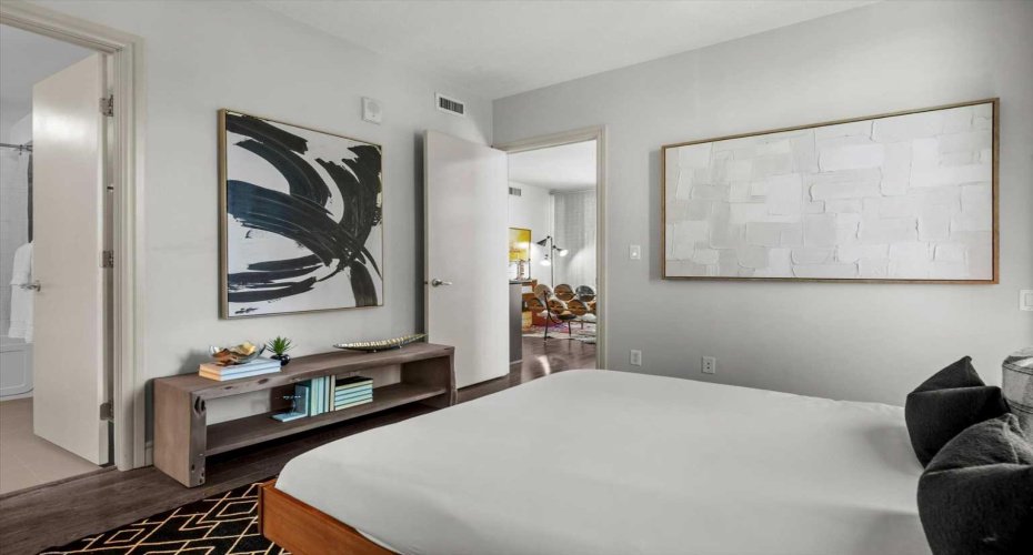 Looking back across the primary bedroom toward the closets and ensuite, the room shows its full depth. There is real storage here and a bathroom that does not require a hallway trek.