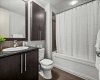 The primary ensuite is tidy and well finished with dark cabinetry, a granite vanity top, and a full tub and shower. It matches the quality of finishes found throughout the rest of the suite.