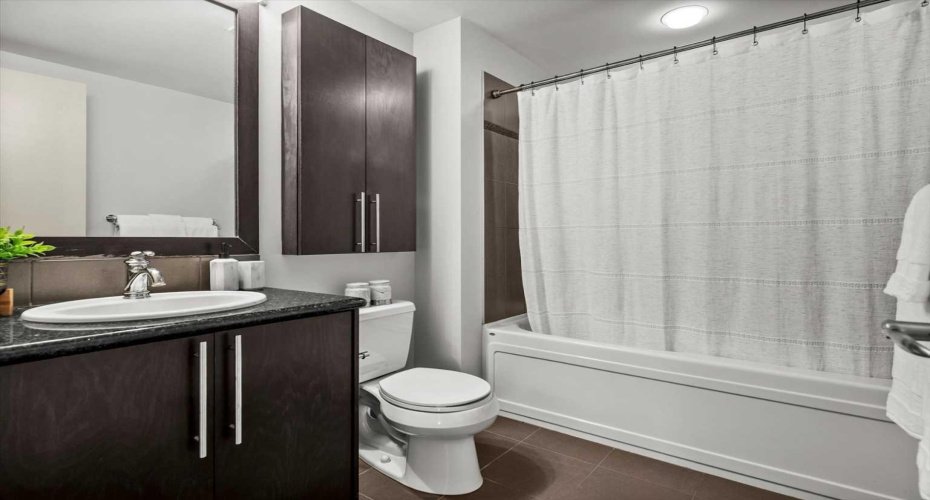 The primary ensuite is tidy and well finished with dark cabinetry, a granite vanity top, and a full tub and shower. It matches the quality of finishes found throughout the rest of the suite.