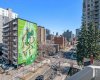The full mural in view from the balcony, with the downtown Calgary skyline stretching out behind it and the Calgary Tower sitting in the distance. This is what you look at on a weekday morning with your coffee and on a Saturday evening before heading out.