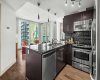 The kitchen is the heartbeat of this open floor plan and opens directly to the living room, where two walls of floor-to-ceiling windows bring the neighbourhood in. The large street mural visible from inside adds a personality to the view that no high-floor unit could replicate.