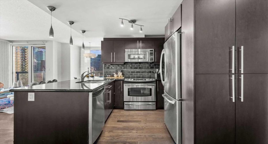 Espresso stained cabinetry, stainless steel appliances, and plenty of storage make this a kitchen people actually cook in. It handles a quiet Tuesday dinner just as well as a Saturday night with friends.