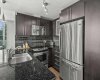 Black granite countertops and a dark subway tile backsplash give the kitchen a cohesive, intentional look. The island sink keeps whoever is cooking part of the conversation.