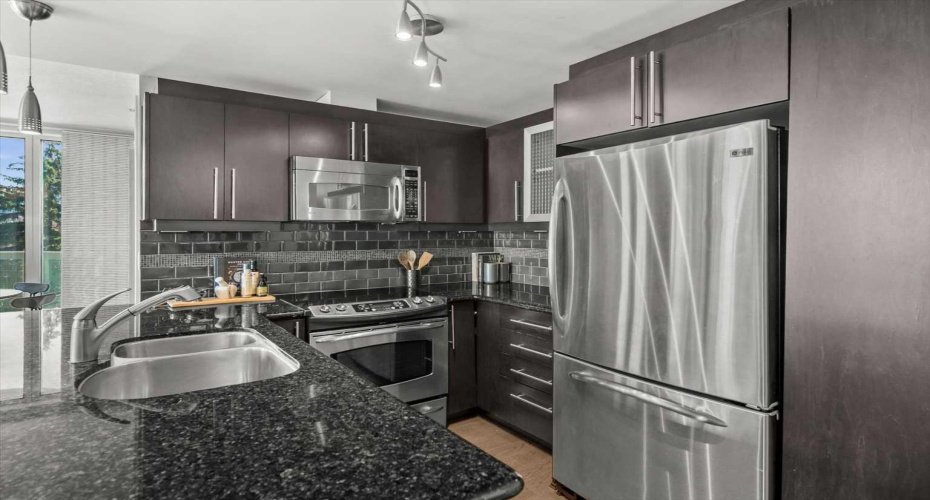 Black granite countertops and a dark subway tile backsplash give the kitchen a cohesive, intentional look. The island sink keeps whoever is cooking part of the conversation.