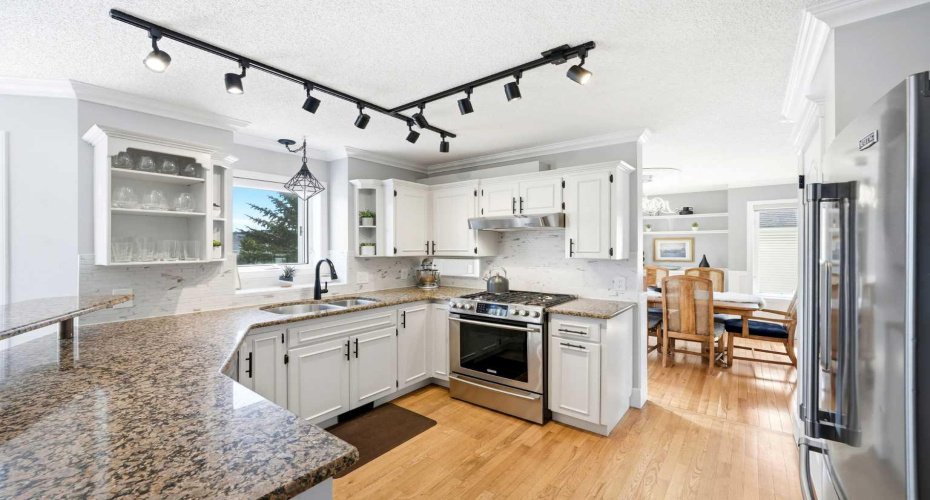 A stylishly updated kitchen with granite counters, gas range, and stainless steel appliances.