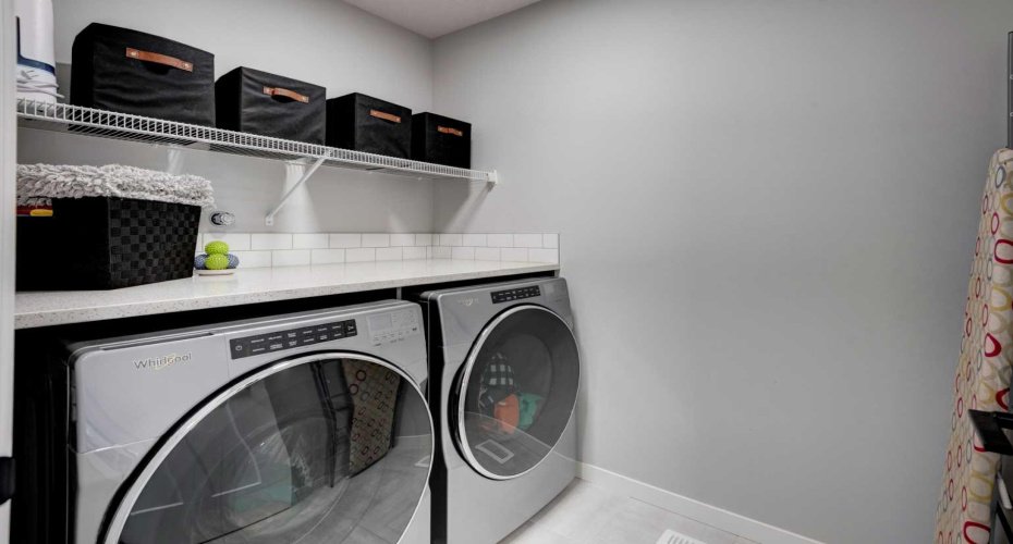Upstairs laundry room with quartz counter and storage shelving