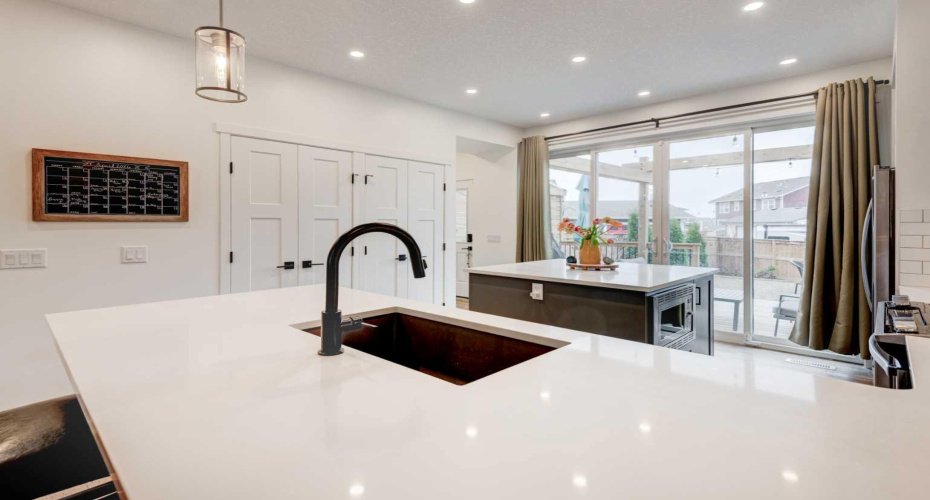 Kitchen with quartz countertops, island with storage, breakfast bar seating, stainless steel appliances and under mount sink.