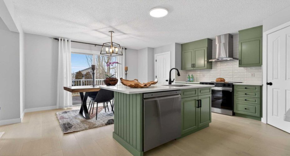 Custom sage-green kitchen, white quartz island, chimney hood fan. Renovated Somerset Calgary home $699,900