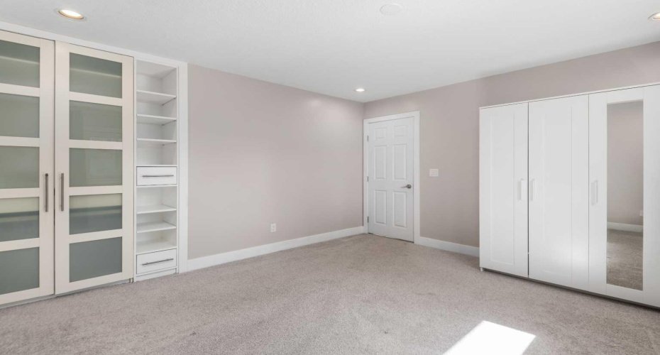 Primary bedroom with built-ins and free-standing wardrobe.