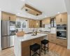 Luxury kitchen showcasing a waterfall quartz island, full-height quartz backsplash with matching veins, gourmet appliance package with built-ins, gas range with pot filler, glass cabinetry, soft-close cabinets, and WiFi-enabled smart appliances including a screen-equipped fridge.