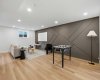 Sophisticated basement lounge featuring a designer feature wall, seamless open-concept layout, and a warm, upscale ambiance perfect for a media room or games area.