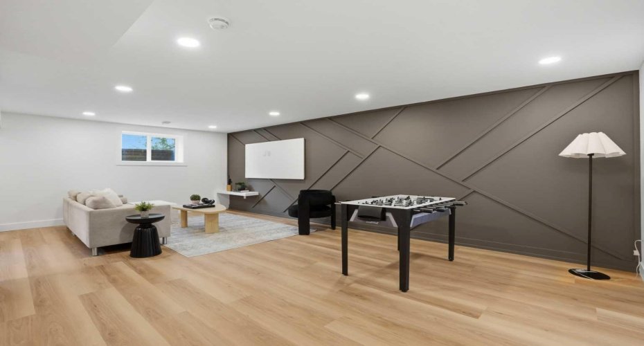 Sophisticated basement lounge featuring a designer feature wall, seamless open-concept layout, and a warm, upscale ambiance perfect for a media room or games area.