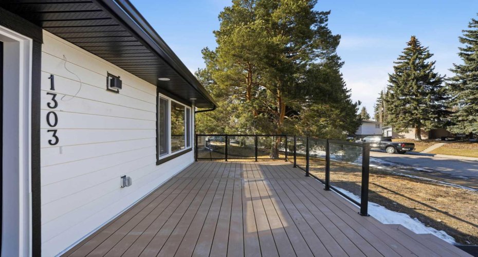 Elegant outdoor space with a massive front deck and glass railings, designed for a luxurious indoor-outdoor lifestyle.
