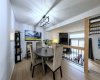 The social hub. A dedicated dining area anchored by an edgy industrial-cage pendant, perfectly positioned overlooking the sunken living room.