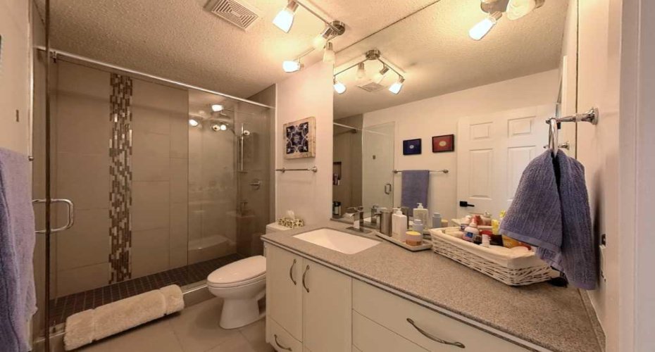 The upper-level main bathroom. Reimagined as a 4-piece retreat with a glass shower enclosure and dual shower heads.
