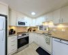 Surgical precision in the kitchen. A highly functional U-shape layout with crisp white cabinetry and a smart pass-through window to keep the prep out of sight.
